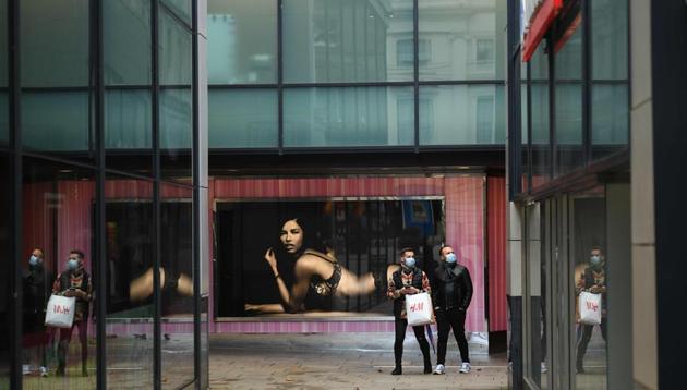 Pedestrians wearing face masks pause beside an advertising poster in a street in Leeds, northern England, on November 1 as England prepares to enter into a second lockdown in an effort to stem soaring Covid-19 infections.(AFP)