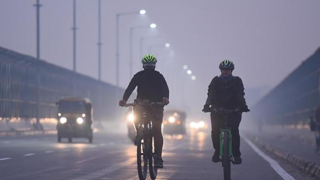 Cyclists ride on a road blanketed in thick haze during early hours at Vikas Marg in New Delhi on Saturday.(Raj K Raj/HT PHOTO)