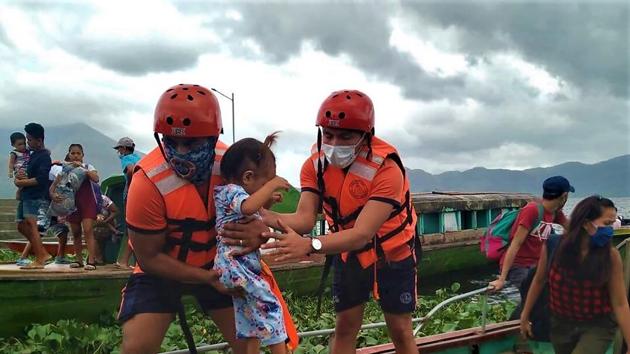 In this photo provided by the Philippine Coast Guard, members of the Philippine Coast Guard carry a child as they are evacuated to safer ground in Camarines Sur province, eastern Philippines on Saturday.(AP Photo)