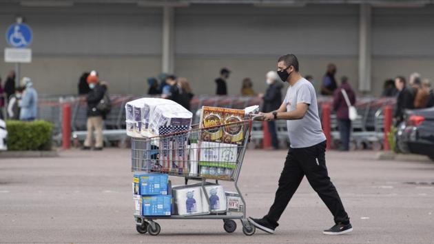 A shopper walks away with a full cart as others queue outside a major supermarket in Leicester on November 1. Prime Minister Johnson had hoped regional restrictions introduced in October would be enough to push the numbers of new infections down. But government scientific advisers predict that on the outbreak’s current trajectory, demand for hospital beds will exceed capacity by the first week of December. (Joe Giddens / PA via AP)