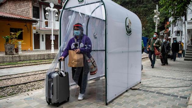 A visitor goes through a disinfection chamber in Aguas Calientes, on her way to Machi Picchu on November 1. For safety reasons, only 675 tourists will be able to access the site per day --just 30% of the number of visitors pre-pandemic. The first train of tourists arrived the same morning as the reopening, at Machu Picchu Pueblo, the village closest to the citadel. (Ernesto Benavides / AFP)