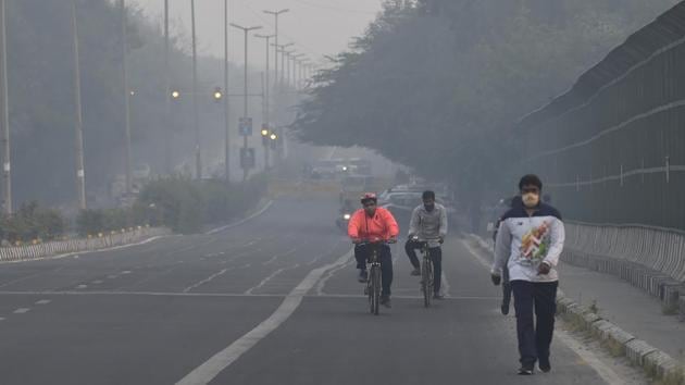 People take a walk along a road as thick haze engulfs the city, in New Delhi on November 1 morning. (PTI) People take a walk along a road as thick haze engulfs the city, in New Delhi on November 1 morning. (PTI)