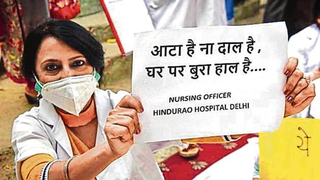 A nursing staff member of Hindu Rao Hospital hold a placard during the protest on Monday.(Sanchit Khanna/HT PHOTO) A nursing staff member of Hindu Rao Hospital hold a placard during the protest on Monday.(Sanchit Khanna/HT PHOTO)