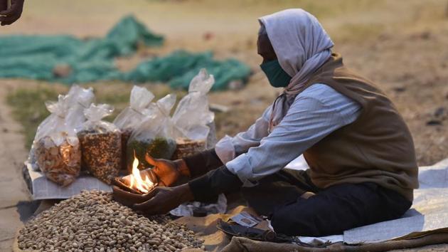 A street hawker seen sitting next to a fire on a cold evening near Teen Murty bus stop, in New Delhi, India, on Monday, November 2, 2020. (Sanjeev Verma/HT photo) A street hawker seen sitting next to a fire on a cold evening near Teen Murty bus stop, in New Delhi, India, on Monday, November 2, 2020. (Sanjeev Verma/HT photo)