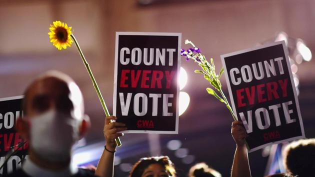 Activists hold up flowers and signs stating "Count Every Vote" across the street from where votes are still being counted, two days after the 2020 US presidential election, in Philadelphia on November 5. Both sides held rallies in Philadelphia as election staffers slowly counted through thousands of mail-in ballots that could decide Pennsylvania’s crucial 20 Electoral College votes. (Mark Makela / REUTERS) Activists hold up flowers and signs stating "Count Every Vote" across the street from where votes are still being counted, two days after the 2020 US presidential election, in Philadelphia on November 5. Both sides held rallies in Philadelphia as election staffers slowly counted through thousands of mail-in ballots that could decide Pennsylvania’s crucial 20 Electoral College votes. (Mark Makela / REUTERS)