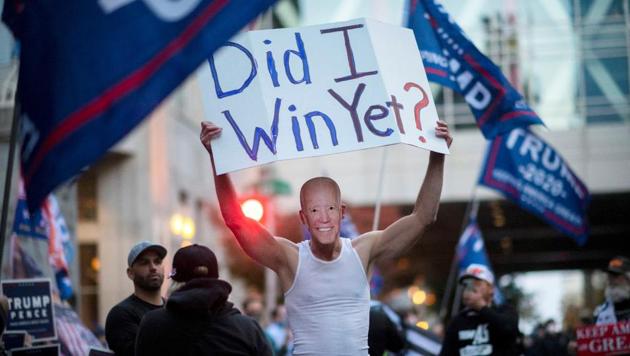 A Donald Trump supporter carries a sign while wearing a mask of US Democratic presidential nominee Joe Biden during a protest outside of the Philadelphia Convention Center, where votes are still being counted two days after the presidential election, in Philadelphia, Pennsylvania, US, November 5, 2020 (REUTERS/Mark Makela)