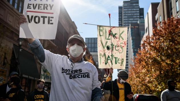 A demonstrator wearing a protective mask holds a "Count Every Vote" sign at a protest in front of the Convention Center during the 2020 Presidential election in Philadelphia, Pennsylvania, U.S., on Tuesday, Nov. 5, 2020.(Bloomberg photo)