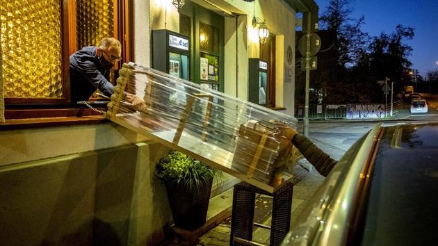 A box with food slides down to car from a window of the apple cider restaurant 'Zum Lahmen Esel' in Frankfurt, Germany, on November 5. Due to the new partial lockdown to avoid the coronavirus spread, the restaurant which has been in operation since 1807, now offers cider and food to go in a self-made drive through set up. (Michael Probst / AP) A box with food slides down to car from a window of the apple cider restaurant 'Zum Lahmen Esel' in Frankfurt, Germany, on November 5. Due to the new partial lockdown to avoid the coronavirus spread, the restaurant which has been in operation since 1807, now offers cider and food to go in a self-made drive through set up. (Michael Probst / AP)