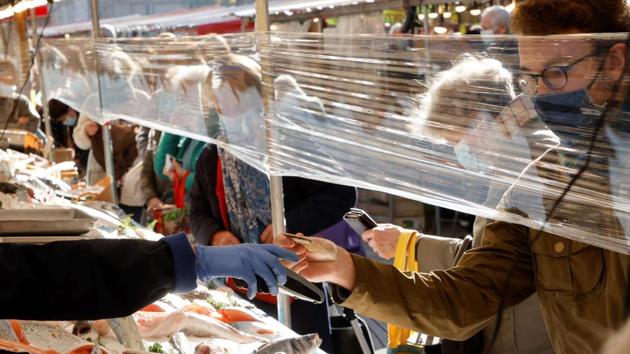 People wearing face masks shop at an open market in Paris on November 4. Owing to a rise in infection that is proving to be deadlier than the first wave, French President Emmanuel Macron put lockdown curbs into effect on October 30, in a second attempt at strongholding the contagion. (Ludovic Marin / AFP)