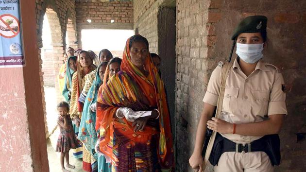 A security personnel stands guard as voters stand in a queue to cast their votes during the polling of third and final phase of Bihar assembly election in Vaishali on Saturday. (ANI) A security personnel stands guard as voters stand in a queue to cast their votes during the polling of third and final phase of Bihar assembly election in Vaishali on Saturday. (ANI)