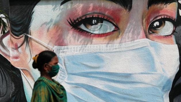 A woman walks past a graffiti of a girl wearing a protective mask amidst the spread of the coronavirus disease in Mumbai. (REUTERS) A woman walks past a graffiti of a girl wearing a protective mask amidst the spread of the coronavirus disease in Mumbai. (REUTERS)