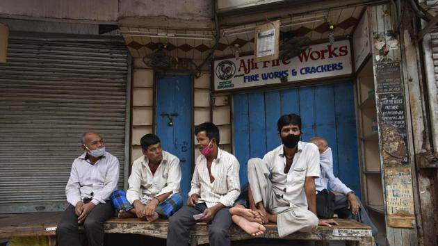 Workers bide time outside a shuttered firecracker shop after the Delhi government banned their sale ahead of Diwali in New Delhi on November 8. Jain also called out people’s laxity in adhering to Covid-19 safe behaviour and urged them to treat the mask as the only medicine till a vaccine is available. (Vipin Kumar / HT Photo)