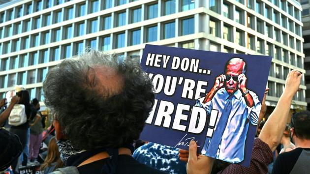 A supporter of president-elect Joe Biden hoists a sign on Black Lives Matter Plaza across from the White House in Washington, DC on November 7, 2020, after Joe Biden was declared the winner of the 2020 presidential election.(AFP)