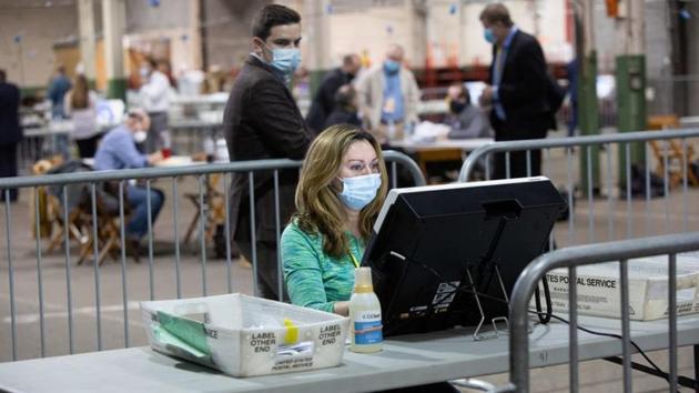 An observer watches a poll worker tabulate ballots at the Allegheny County Election Warehouse after the election in Pittsburgh, Pennsylvania, US. (REUTERS)