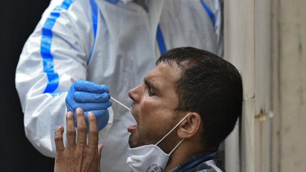 A man gives a swab sample for coronavirus detection tests, at Nehru Homoeopathic Medical College and Hospital in Defense Colony, New Delhi.(Biplov Bhuyan/HT PHOTO)