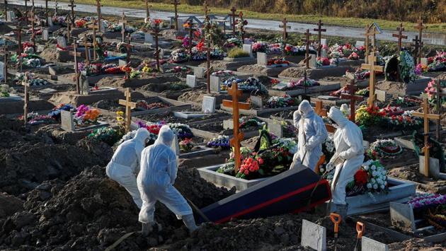 Gravediggers wearing personal protective equipment (PPE) lower a coffin while burying a person in the special purpose section of a graveyard for Covid-19 victims on the outskirts of Saint Petersburg, Russia on November 6. A global second wave is testing already strained health care systems once more. (Anton Vaganov / REUTERS)