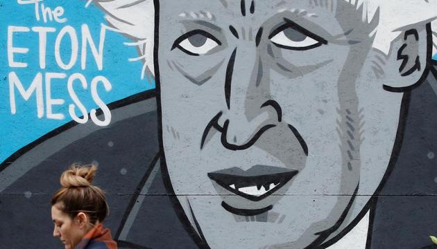A woman walks past a caricature of Britain's Prime Minister Boris Johnson in the boarded up window of a closed pub in Manchester, Britain.(REUTERS)