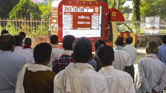 Locals watch the election results on a big screen during counting day of Bihar Assembly polls in Patna on Tuesday.(PTI)