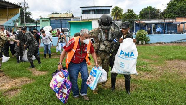 US Army soldiers escort civilians and military members to load emergency supplies on a helicopter for delivery to people isolated by Hurricane Eta's effects at Choloma, Honduras on November 8 . Eta slammed into Central America last week as a Category 4 hurricane and left swathes of the country under water. Two major rivers overflowed in Honduras’ Sula Valley economic heartland, trapping tens of thousands of people. (Staff Sgt.Elijaih Tiggs / U.S. Air Force via REUTERS)