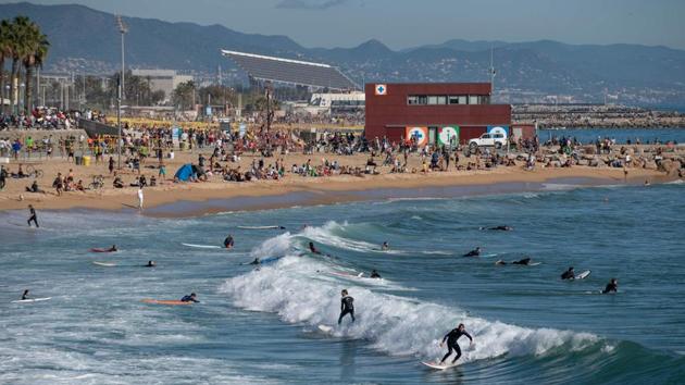 People sunbathe and surf at the Bogatell beach in Barcelona, Spain on November 8. While the new vaccine being developed by Pfizer and BioNTech will take time to arrive, authorities are hoping that once winter is passed, it will stem further outbreaks next year. (Josep Lago / AFP) People sunbathe and surf at the Bogatell beach in Barcelona, Spain on November 8. While the new vaccine being developed by Pfizer and BioNTech will take time to arrive, authorities are hoping that once winter is passed, it will stem further outbreaks next year. (Josep Lago / AFP)