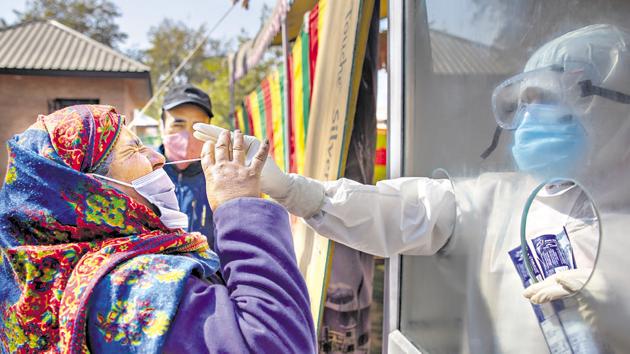 A Kashmiri woman reacts as a health worker takes a nasal swab sample to test for Covid-19 in Srinagar. (AP) A Kashmiri woman reacts as a health worker takes a nasal swab sample to test for Covid-19 in Srinagar. (AP)