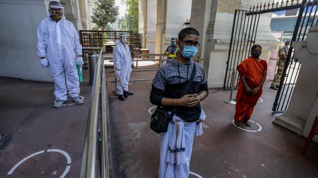 Security guards in protective suits and visitors waiting distantly to enter the Indian Museum, as it reopens after nearly eight months of shutdown since March due to the coronavirus pandemic, in Kolkata on November 10. (Bikas Das / AP)
