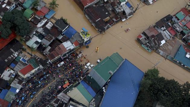 In this photo, residents stay along a road as rescuers use rubber boats to get to people trapped in their homes due to high floodwaters caused by Typhoon Vamco in Marikina, Philippines, on November 12. (Ace Morandante / Malacanang Presidential Photographers Division via AP)