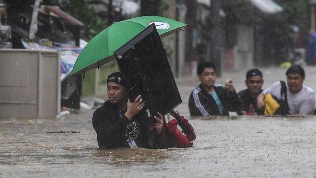 A man carries a television as residents make their way through a flooded street to shelter after Typhoon Vamco hit the area in Marikina City, suburban Manila on November 12. Nearly three million households in and around Manila were without power as people waded through waist-high floods, carrying valuables and pets, Reuters reported. (Ted Aljibe / AFP) A man carries a television as residents make their way through a flooded street to shelter after Typhoon Vamco hit the area in Marikina City, suburban Manila on November 12. Nearly three million households in and around Manila were without power as people waded through waist-high floods, carrying valuables and pets, Reuters reported. (Ted Aljibe / AFP)