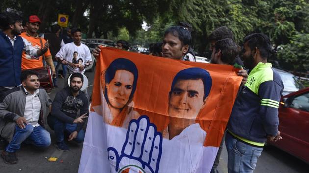 A Congress party worker holds a flag with Sonia Gandhi and Rahul Gandhi’s faces.(Burhaan Kinu/HT PHOTO)