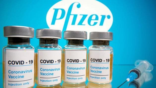 Vials with a sticker reading, "Covid-19 / Coronavirus vaccine / Injection only" and a medical syringe are seen in front of a displayed Pfizer logo.(Reuters File Photo)