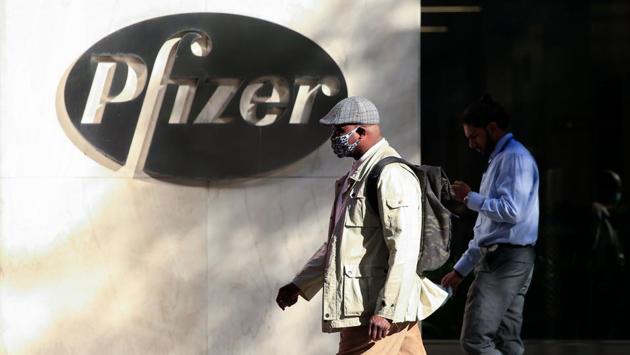 Commuters walk past the Pfizer world headquarters in New York on November 9. With potential vaccine for Covid-19 months away from widespread distribution, health experts are warning of a grim early December as infections surge throughout America and Europe. (Kena Betancur / AFP)