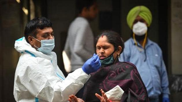 A health worker in PPE coveralls collects a swab sample from a woman for coronavirus testing, in Jahangirpuri, New Delhi.(Sanchit Khanna/HT PHOTO)