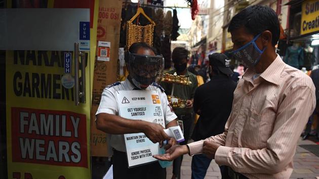 A security guard checks the body temperature of a customer outside a shop in a market ahead of Diwali, the festival of lights, amid Covid-19 coronavirus pandemic in New Delhi. (AFP) A security guard checks the body temperature of a customer outside a shop in a market ahead of Diwali, the festival of lights, amid Covid-19 coronavirus pandemic in New Delhi. (AFP)