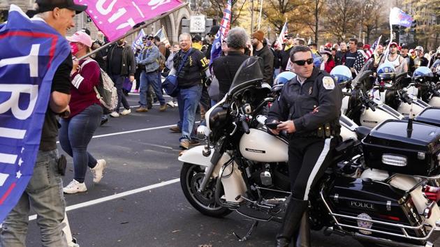 A police officer sits by his vehicle people dressed in clothing with “Proud Boys” on it march down Pennsylvania Avenue on November 14 in Washington D.C. The marchers included members of the Proud Boys, a neo-fascist group known for street brawling with ideological opponents at political rallies, AP reported. (Jacquelyn Martin / AP) A police officer sits by his vehicle people dressed in clothing with “Proud Boys” on it march down Pennsylvania Avenue on November 14 in Washington D.C. The marchers included members of the Proud Boys, a neo-fascist group known for street brawling with ideological opponents at political rallies, AP reported. (Jacquelyn Martin / AP)