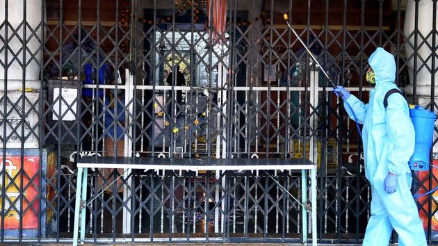 An employee, wearing a PPE kit, sanitizes the premises of a Hindu temple in Mumbai.(PTI)