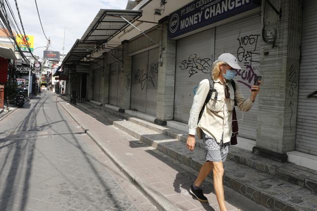 FILE - In this April 14, 2020, file photo, a foreign tourist walks along an empty road lined with closed shops in Bali, Indonesia (AP Photo/Firdia Lisnawati, File). FILE - In this April 14, 2020, file photo, a foreign tourist walks along an empty road lined with closed shops in Bali, Indonesia (AP Photo/Firdia Lisnawati, File).