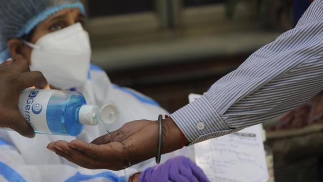A commuter sanitizes their hands while collecting a result report for a rapid coronavirus test as Noida authorities conduct random checks on commuters from Delhi at DND border, in Noida on Wednesday. (Sunil Ghosh /HT Photo)