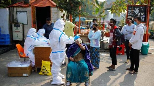 A healthcare worker collects a swab sample from a woman in Noida on November 19.(Reuters)