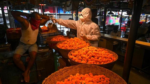 A health worker (R) checks the body temperature of a shopkeeper during a Covid-19 testing drive at a flower market in Mumbai on November 19. India’s climb past the latest million came a day after Prime Minister Narendra Modi reviewed the country’s preparedness of vaccine delivery, distribution and administration. (Indranil Mukherjee / AFP)