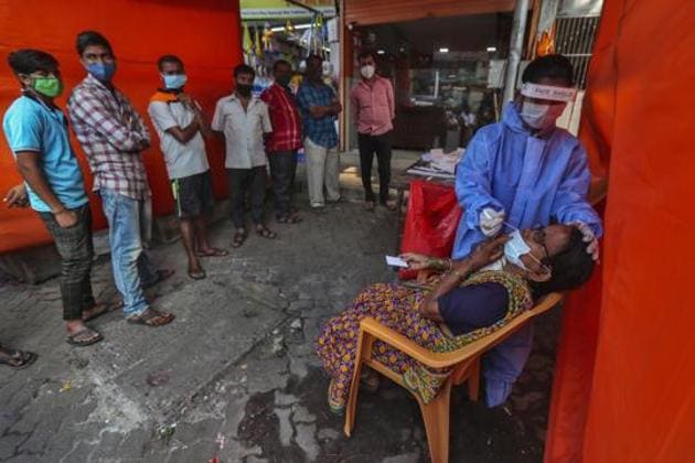 A health worker takes a nasal swab sample of a woman to test for Covid-19 as others wait their turn in Mumbai on November 19.(AP) A health worker takes a nasal swab sample of a woman to test for Covid-19 as others wait their turn in Mumbai on November 19.(AP)