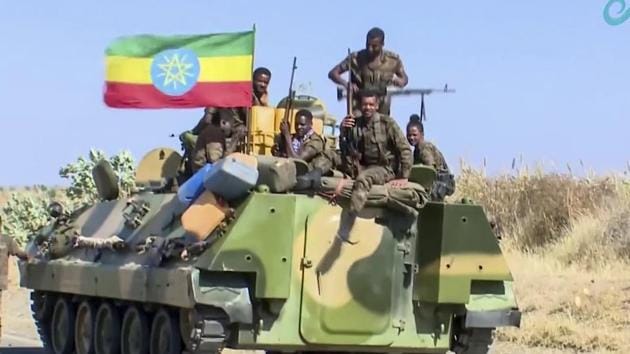 Ethiopian military sitting on an armored personnel carrier next to a national flag, on a road in an area near the border of the Tigray and Amhara regions of Ethiopia.(AP)