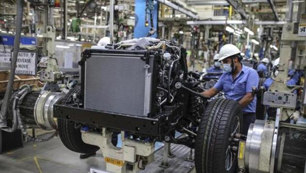 Workers labour at a chassis assembly line on the Innova Crysta compact multi-purpose vehicle (MPV) production line at the Toyota Kirloskar Motor Ltd. plant in Bidadi, Karnataka.(Bloomberg File Photo)
