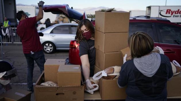 Jailine Guerrero (C), helps load food into cars at a free Thanksgiving food distribution event by the Culinary Academy Las Vegas on November 21. Nevada is the latest to announce new restrictions such as mandatory masks indoors and outdoors and seating limits on casinos, restaurants and private gatherings such as Thanksgiving dinners, despite having avoided any curbs earlier. The new restrictions come into effect on November 24. (John Locher / AP) Jailine Guerrero (C), helps load food into cars at a free Thanksgiving food distribution event by the Culinary Academy Las Vegas on November 21. Nevada is the latest to announce new restrictions such as mandatory masks indoors and outdoors and seating limits on casinos, restaurants and private gatherings such as Thanksgiving dinners, despite having avoided any curbs earlier. The new restrictions come into effect on November 24. (John Locher / AP)