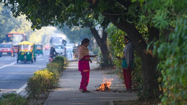 Women warm themselves next to a fire at RK Puram in New Delhi on November 22. After the Western Disturbance passes, cold winds will again start blowing from the region and the mercury is set to dip again from November 27, HT reported. (Amal KS / HT Photo) 