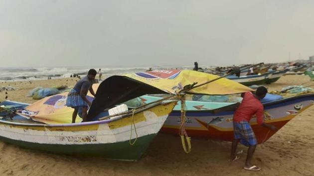 Fishermen cover their boats at Marina Beach during heavy rain, triggered by Cyclone Nivar, in Chennai on Tuesday.(PTI PHOTO.) Fishermen cover their boats at Marina Beach during heavy rain, triggered by Cyclone Nivar, in Chennai on Tuesday.(PTI PHOTO.)