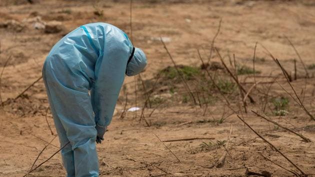 A health worker reacts before the burial of a Central Reserve Police Force (CRPF) officer who died from the coronavirus disease at a graveyard in New Delhi.(REUTERS) A health worker reacts before the burial of a Central Reserve Police Force (CRPF) officer who died from the coronavirus disease at a graveyard in New Delhi.(REUTERS)