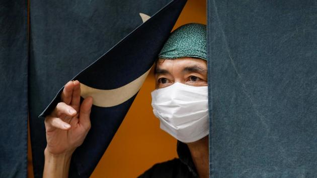 Haga rolls a shop curtain at the entrance of Shirohachi in Tokyo on November 20. Now he is using $29,000 worth of government’s subsidies to keep Shirohachi running till its closure in December, Reuters reported. (Issei Kato / Reuters)