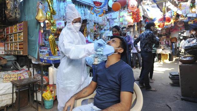 A health worker in a PPE kit collects a sample for Covid-19 test at a market in Mumbai.(PTI)