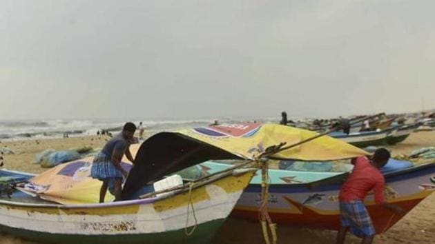 Fishermen cover their boats at Marina Beach during heavy rain, triggered by Cyclone Nivar,in Chennai on Tuesday.(PTI Photo)