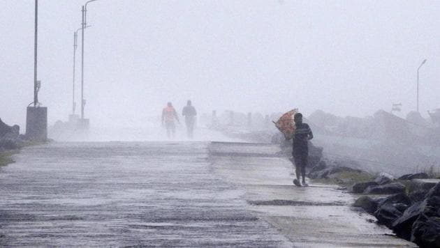 A man tries to hold his umbrella against strong winds at the Kasimedu Harbor on the Bay of Bengal coast in Chennai, India, Wednesday, Nov.25, 2020.(AP photo)